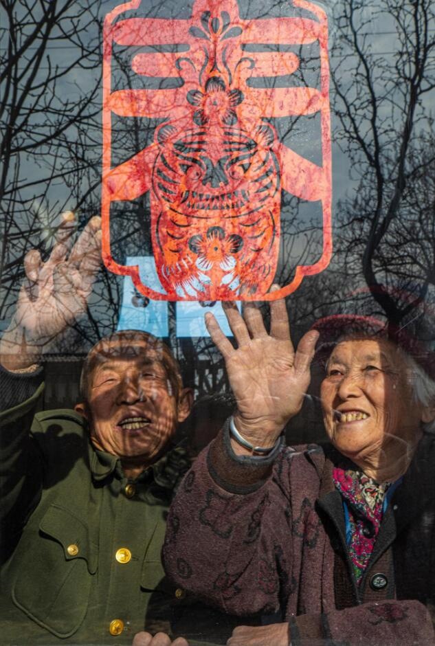 臘月里，霍州市師莊鄉(xiāng)馮南垣村村民師榮光(左)在災后重建的新家里貼窗花。(霍州市委宣傳部供圖)