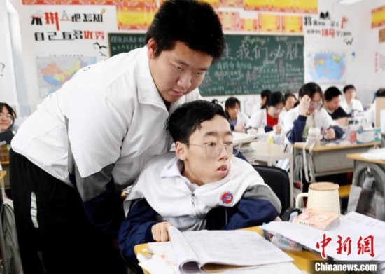 朱金祥(左)把鐘華強放到課堂座位上后，都要把他擺正好，確認安全后才回到自己的座位上。 卓忠偉 攝