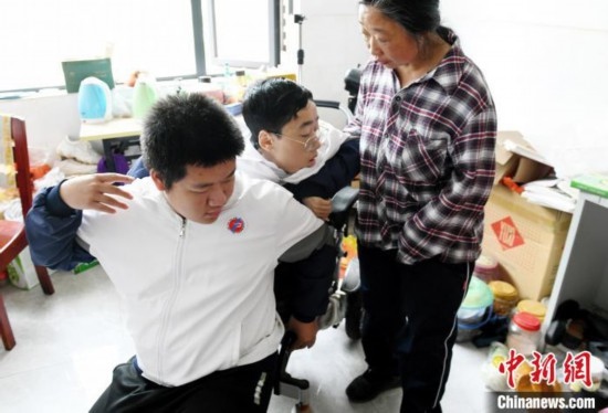 江西省南康中學北校區(qū)的高三學生朱金祥(左)來到學校給鐘華強母子安排的公寓，準備背他去課堂上課。 卓忠偉 攝