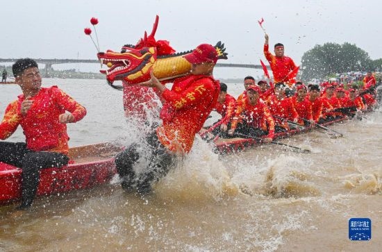 6月22日，在湖南省岳陽市湘陰縣湘江臨資口水域，參加龍舟賽的隊員接“龍頭”下水。