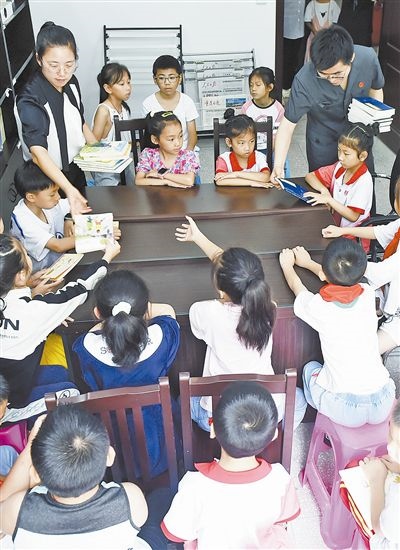  圖④：法院干警為留守兒童發(fā)放暑假讀物。