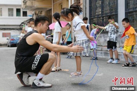 圖為大學(xué)生志愿者在教孩子們學(xué)跳繩。廖光福 攝