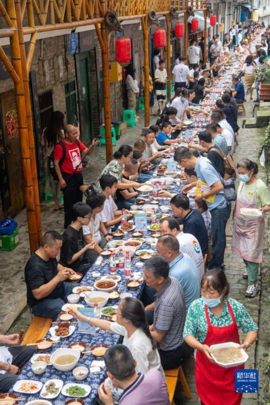 7月29日，在重慶市綦江區(qū)安穩(wěn)鎮(zhèn)，人們在“苗家伏羊節(jié)”上吃長桌宴。新華社記者 唐奕 攝