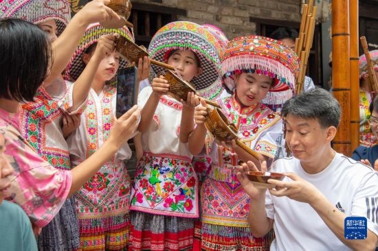 7月29日，在重慶市綦江區(qū)安穩(wěn)鎮(zhèn)，當(dāng)?shù)鼐用裨凇懊缂曳蚬?jié)”上用傳統(tǒng)習(xí)俗向游客表達(dá)祝福。新華社記者 唐奕 攝