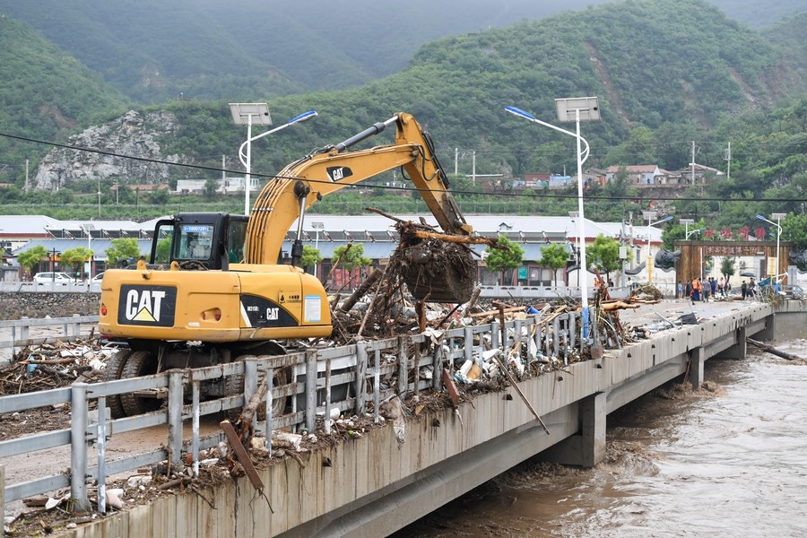 8月1日，在北京市門頭溝區(qū)水峪嘴村村口，一臺(tái)挖掘機(jī)在清理阻斷橋梁交通的雜物。目前該條道路已經(jīng)疏通完成。新華社記者 鞠煥宗 攝