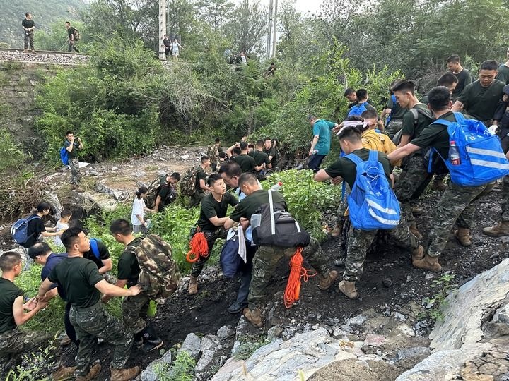 8月2日，Z180次受困列車(chē)的旅客在武警北京總隊(duì)機(jī)動(dòng)第三支隊(duì)官兵的幫助下徒步前往轉(zhuǎn)運(yùn)客車(chē)（手機(jī)照片）。新華社記者 王艷剛 攝