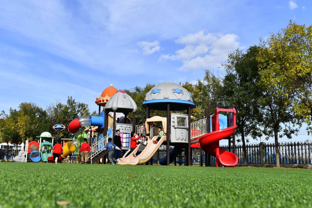 在山東省東營市墾利區(qū)楊廟社區(qū)幼兒園，孩子們在老師的帶領下進行戶外活動（2021年10月19日攝）。新華社記者 郭緒雷 攝