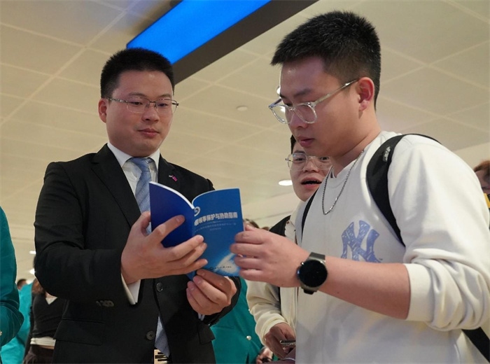 工作人員（左一）在發(fā)放《中國(guó)領(lǐng)事保護(hù)與協(xié)助指南》。 中國(guó)駐迪拜總領(lǐng)事館供圖