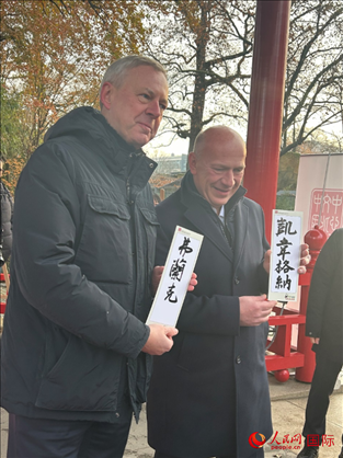 柏林市長韋格納（右）、動物園監(jiān)事會主席布魯克曼（左）手持中國文化中心工作人員現(xiàn)場手書的中文名字。人民網(wǎng)記者 徐馨攝