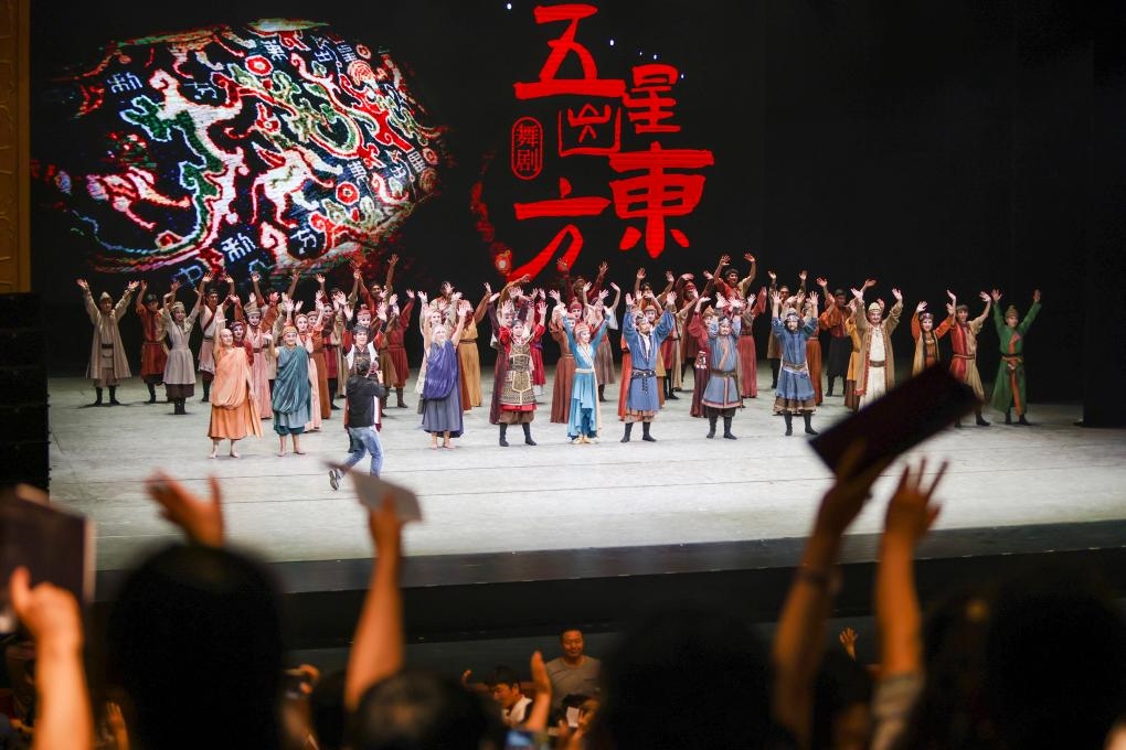2023年7月31日，新疆和田地區(qū)新玉歌舞團在烏魯木齊京劇院演出舞劇《五星出東方》后和觀眾互相揮手致意。這場演出是第六屆中國新疆國際民族舞蹈節(jié)的參演劇目之一，曾榮獲國家“文華獎”等。新華社記者 郝昭 攝