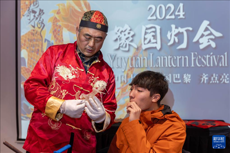 1月28日，在上海豫園舉行的民俗活動(dòng)上，美國(guó)馬斯卡廷中學(xué)學(xué)生在非遺傳承人的指導(dǎo)下吹糖偶。 新華社記者 王翔 攝