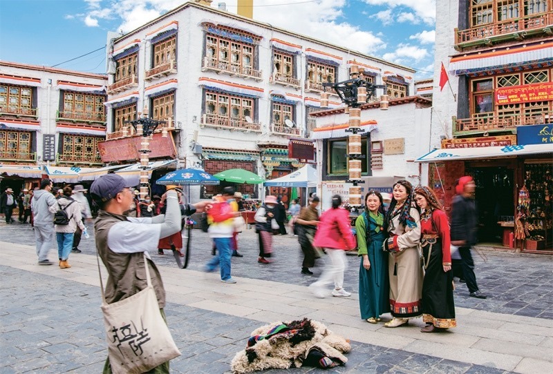 千年八廓街，見證民族團(tuán)結(jié)。2021年7月，習(xí)近平總書記來到位于西藏拉薩老城區(qū)的八廓街，感慨地說：“千年八廓街，是我們各民族建起來的八廓街。各民族文化在這里交流交往交融，我們中華民族的大家庭在這里其樂融融?！眻D為2023年6月13日，游客身著藏裝在八廓街拍照留念。 新華社記者 姜帆/攝