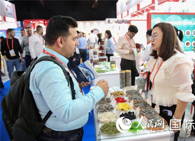 圖為一家中國干果參展企業(yè)代表與采購商洽談。人民網(wǎng) 塔里克·易卜拉欣攝