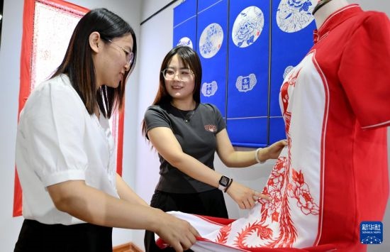 5月31日，在衡水市阜城縣一家剪紙工作室，游客在觀賞帶有剪紙?jiān)氐钠炫邸? width=