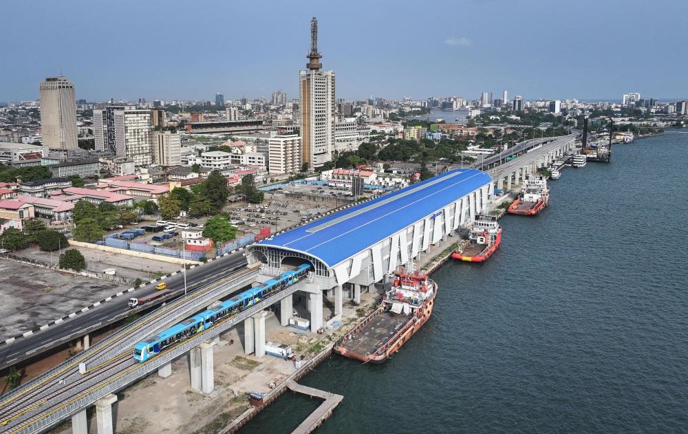 2024年3月2日，在尼日利亞拉各斯，一列輕軌藍線列車駛?cè)氪a頭站（無人機照片）。拉各斯輕軌藍線是西非地區(qū)首條由中國企業(yè)自主設(shè)計、建造、施工、運營的電氣化城市軌道交通項目。新華社記者 韓旭 攝
