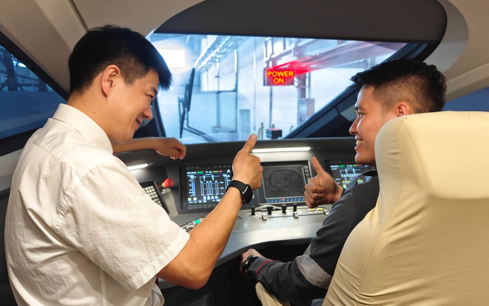 2023年8月25日，在印度尼西亞萬隆的雅萬高鐵德卡魯爾動車所內(nèi)，中國師傅穆振（左）向印尼火車司機塞蒂亞萬講解動車組出庫前的上電作業(yè)。新華社記者 徐欽 攝