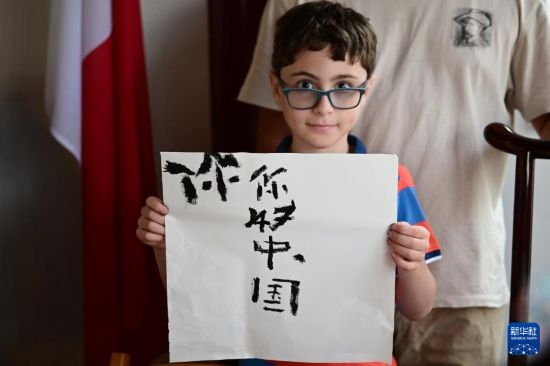 7月4日，在馬耳他桑塔露琪亞市的中國古典園林“靜園”，一名男孩展示他的書法作品。新華社發(fā)（喬納森·博格 攝）