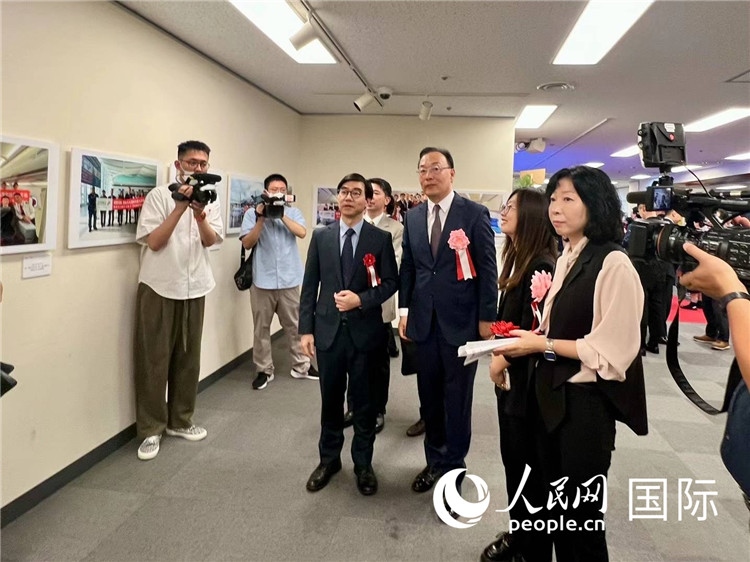 中國國際航空日韓地區(qū)支社支社長馮力為中國駐日本大使館臨時代辦施泳等嘉賓介紹展出圖片。人民網(wǎng) 許可攝