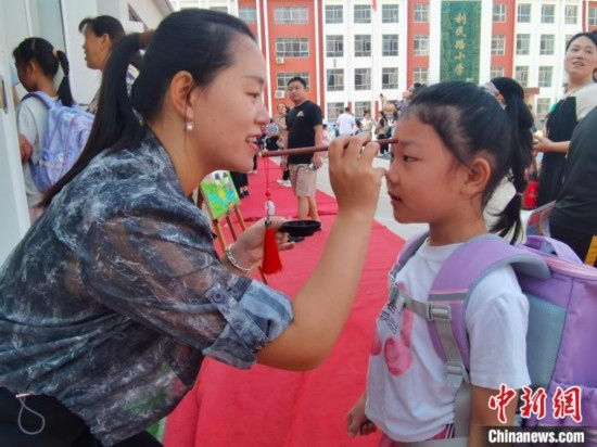 圖為衡水市利民路小學(xué)，老師為學(xué)生點(diǎn)朱砂痣，寓意開啟智慧。張松 攝