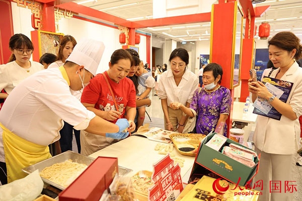 演出前，在天津桂發(fā)祥十八街麻花制作技藝非遺體驗展臺前，泰國民眾體驗天津麻花制作。人民網(wǎng)記者 楊一攝