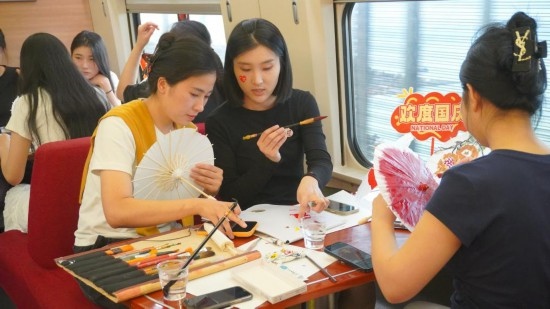 10月1日，旅客們在G1634次列車上給油紙傘作畫。新華社記者周義 攝