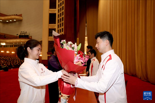 11月15日，一名學(xué)生代表在報(bào)告會(huì)上向乒乓球運(yùn)動(dòng)員馬龍（右）獻(xiàn)花。新華社記者 李明 攝