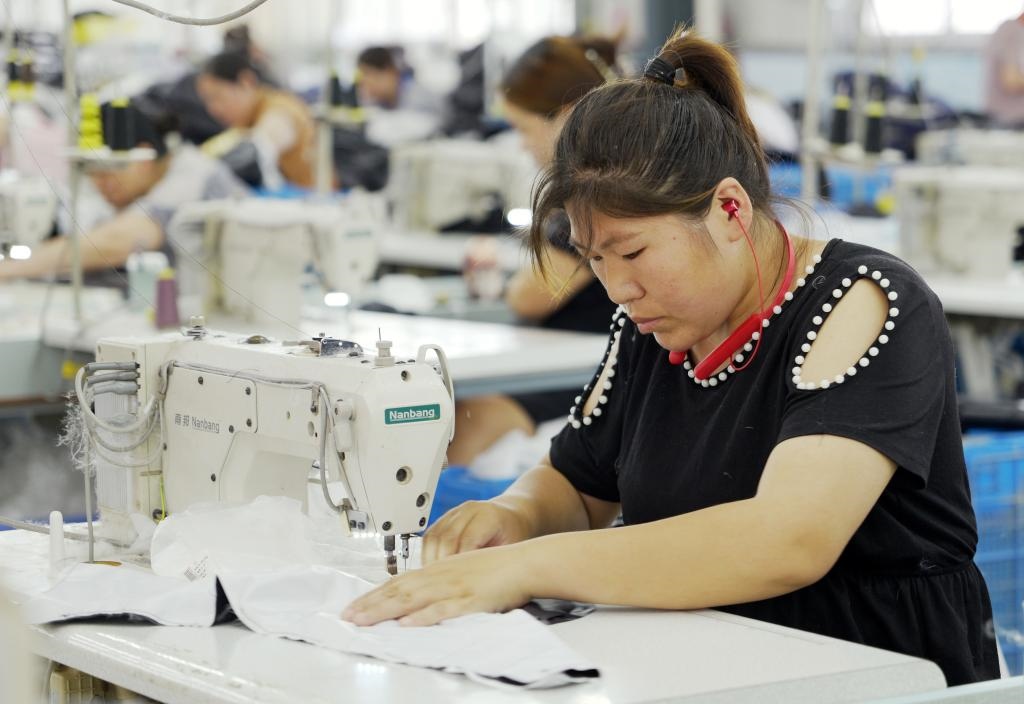 5月20日，村民在李寨村服裝加工廠內(nèi)忙碌。河南省周口市沈丘縣馮營(yíng)鎮(zhèn)李寨村地處豫東平原。近年來，乘著脫貧攻堅(jiān)與鄉(xiāng)村振興政策的東風(fēng)，李寨村積極探索產(chǎn)業(yè)發(fā)展模式，通過“龍頭企業(yè)+村集體經(jīng)濟(jì)+農(nóng)戶”的方式，逐漸發(fā)展形成肉牛養(yǎng)殖、設(shè)施農(nóng)業(yè)、服裝加工、康養(yǎng)民宿等產(chǎn)業(yè)，以產(chǎn)業(yè)振興助力鄉(xiāng)村振興。新華社記者 李嘉南 攝