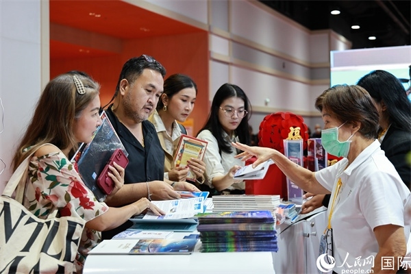 外國觀眾在中國展臺仔細(xì)閱讀赴華旅游介紹，向工作人員咨詢關(guān)于中國美食和景點的詳細(xì)信息。人民網(wǎng)記者 白元琪攝