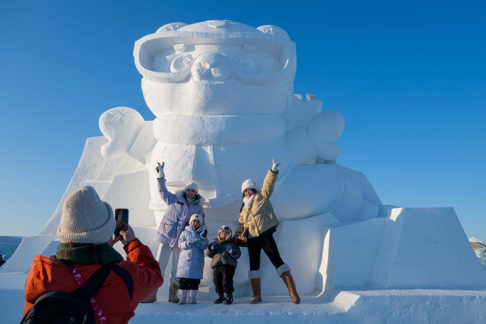 2025年1月3日，在黑龍江哈爾濱冰雪大世界園區(qū)，游客與亞冬會(huì)吉祥物雪雕“濱濱”合影