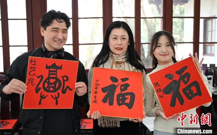1月20日，外籍留學(xué)生和西泠印社社員李硯(中)展示各自創(chuàng)作的福貼。當(dāng)日，來自巴西、馬來西亞、加納、哈薩克斯坦的外籍留學(xué)生在浙江杭州西泠印社體驗(yàn)福貼、春聯(lián)和篆刻，感受古老的中國(guó)傳統(tǒng)文化。中新社記者 王剛 攝