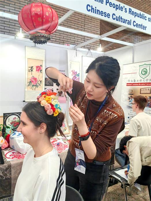 展覽正值羅馬尼亞迎春花節(jié)，國(guó)際中文教師志愿者潘婧穎向游客們介紹了國(guó)家非物質(zhì)文化遺產(chǎn)——福建泉州的簪花文化。布加勒斯特大學(xué)孔子學(xué)院供圖。